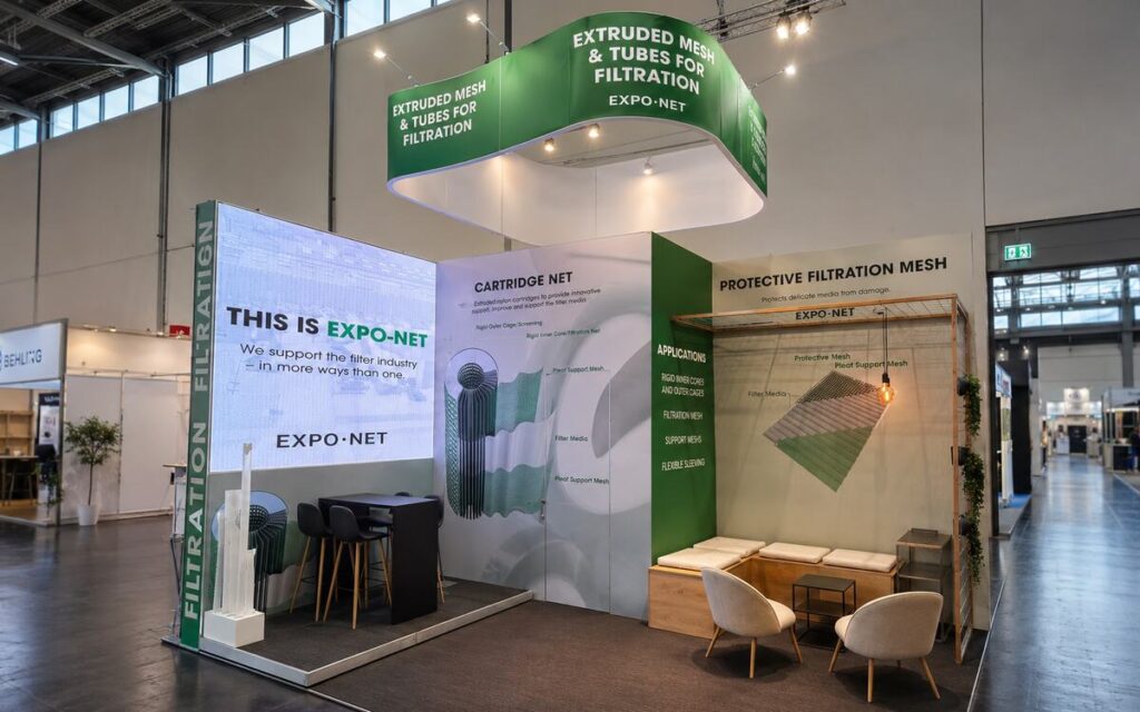 Showroom-lignende messestand for EXPO-NET med produktpræsentation, loungeområde og markant grafik